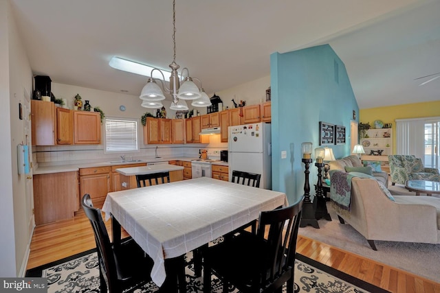 dining room with light hardwood / wood-style flooring, a chandelier, lofted ceiling, and sink