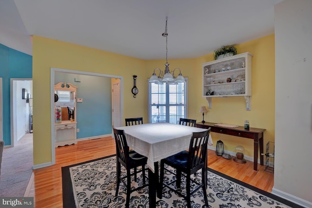 dining area with light hardwood / wood-style floors and a notable chandelier