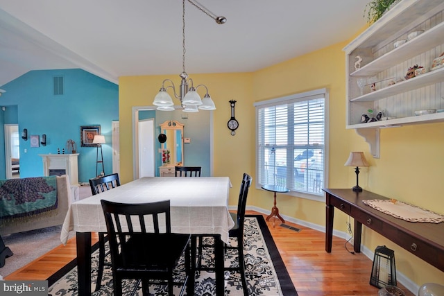 dining room featuring wood-type flooring, lofted ceiling, and a notable chandelier