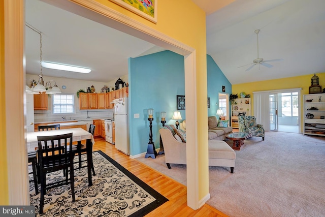 dining area with sink, plenty of natural light, ceiling fan with notable chandelier, and light wood-type flooring