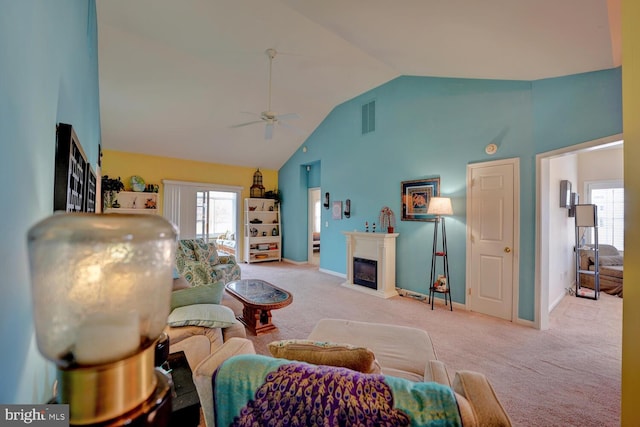 carpeted living room with ceiling fan and high vaulted ceiling