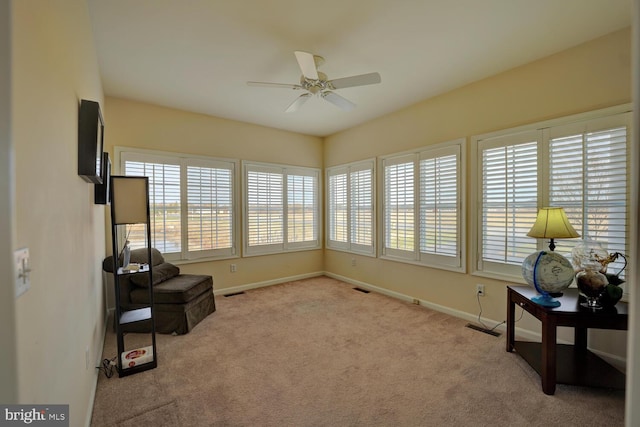 living area with ceiling fan and light colored carpet