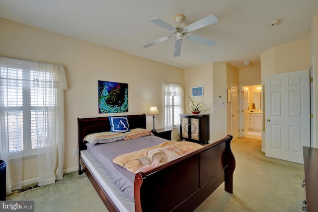 bedroom with ceiling fan, light carpet, and ensuite bath