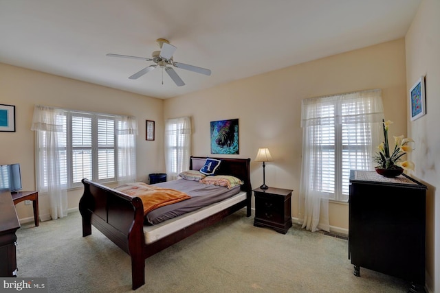 bedroom featuring ceiling fan, light carpet, and multiple windows