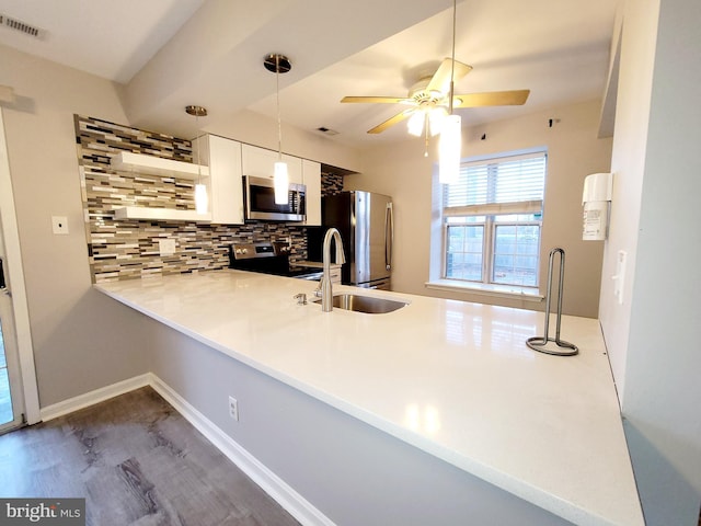 kitchen with backsplash, kitchen peninsula, decorative light fixtures, white cabinetry, and stainless steel appliances