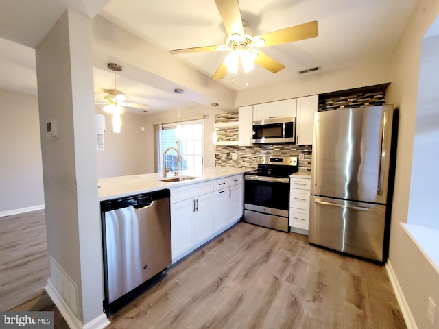 kitchen with sink, light hardwood / wood-style flooring, decorative backsplash, white cabinetry, and stainless steel appliances