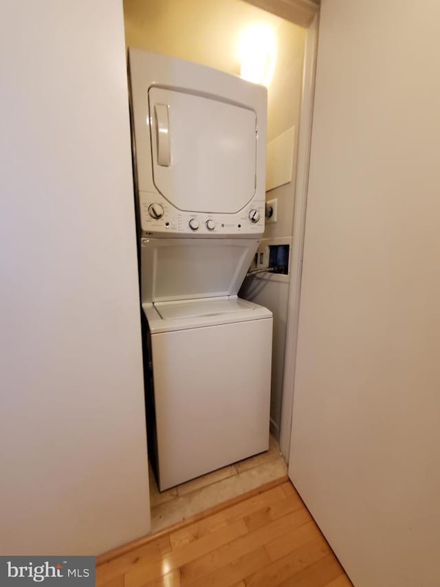 laundry area featuring stacked washing maching and dryer and light hardwood / wood-style flooring