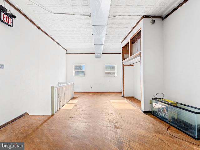 basement with light hardwood / wood-style flooring and crown molding