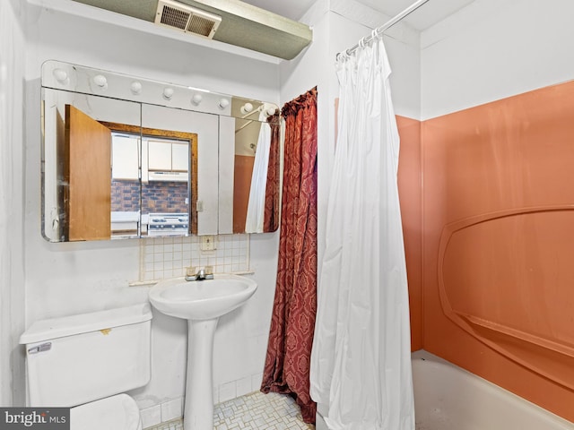 full bathroom featuring sink, shower / bath combo, toilet, and backsplash