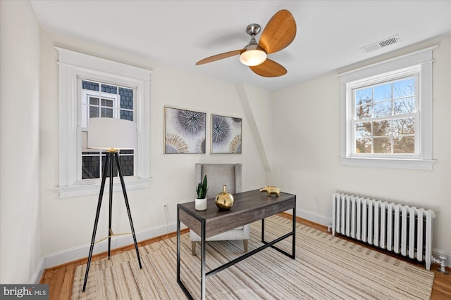 home office with ceiling fan, radiator heating unit, and light wood-type flooring