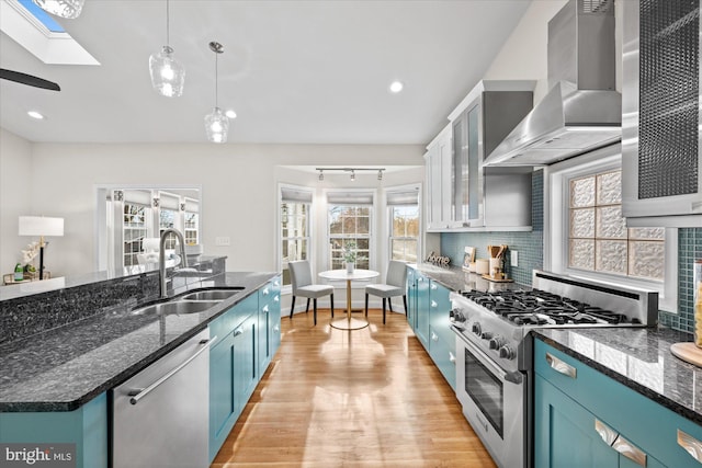 kitchen with a healthy amount of sunlight, sink, stainless steel appliances, and wall chimney range hood