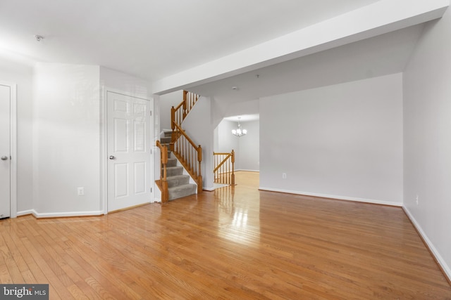 empty room featuring a chandelier and light wood-type flooring