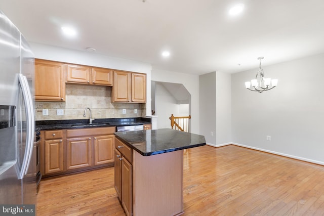 kitchen featuring sink, light hardwood / wood-style flooring, appliances with stainless steel finishes, a kitchen island, and decorative backsplash