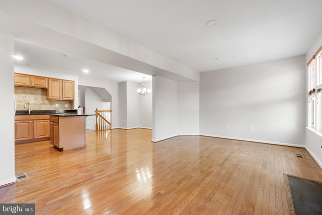 living room with a chandelier, sink, and light hardwood / wood-style flooring