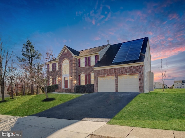 view of front facade with a yard, a garage, and solar panels