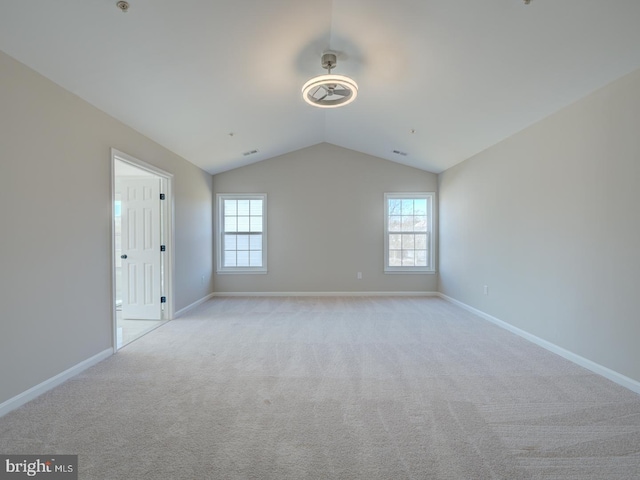 carpeted spare room featuring lofted ceiling