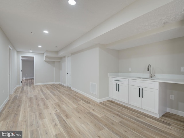 basement featuring sink and light hardwood / wood-style flooring