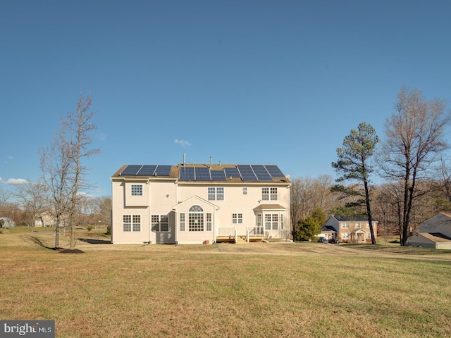 rear view of house with solar panels and a yard