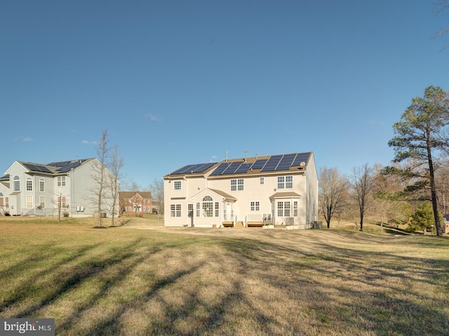 rear view of property featuring solar panels and a yard