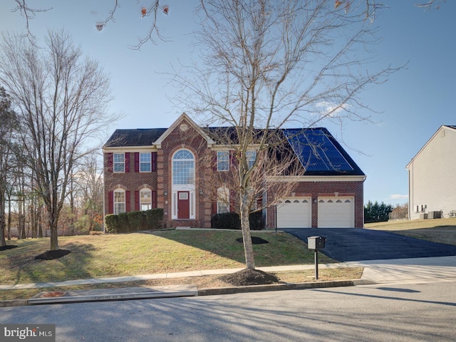 colonial inspired home with solar panels, a garage, and a front yard