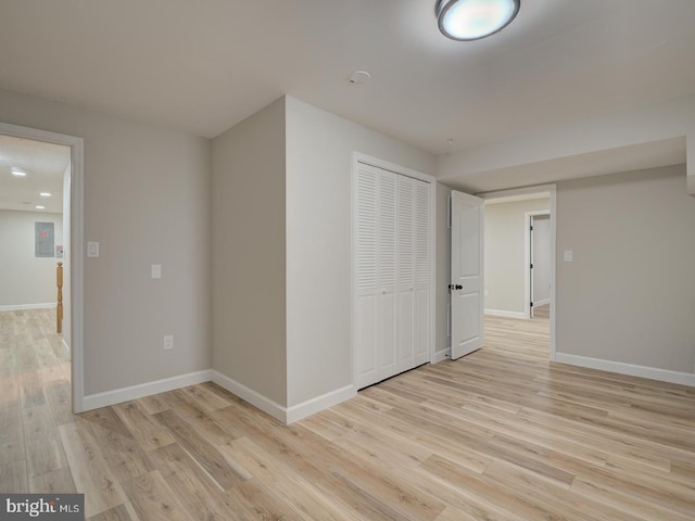 empty room with electric panel and light hardwood / wood-style flooring