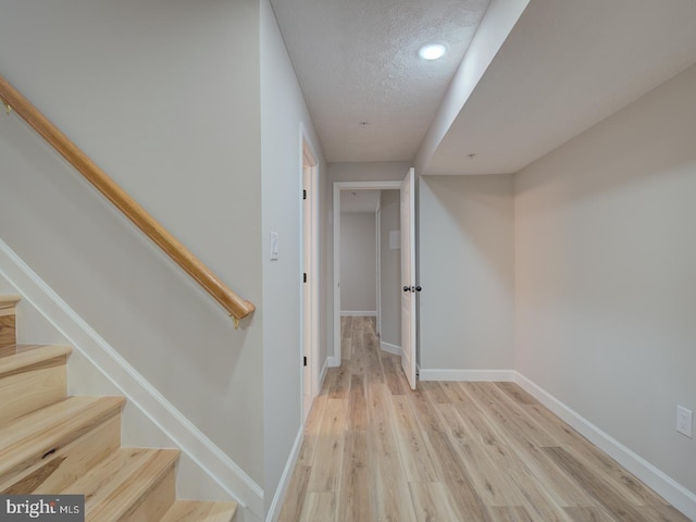 hall featuring a textured ceiling and light wood-type flooring