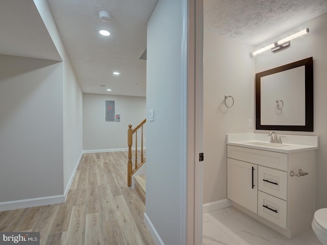 bathroom with hardwood / wood-style floors, vanity, toilet, and a textured ceiling