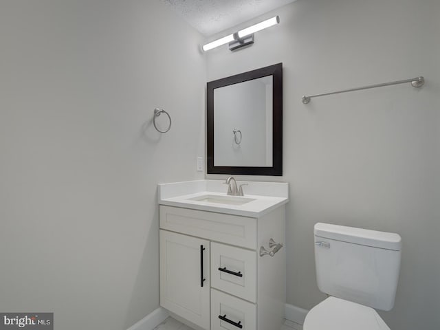 bathroom featuring vanity, a textured ceiling, and toilet