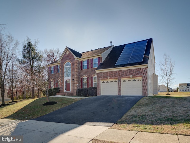 view of front of house with solar panels, a garage, and a front lawn