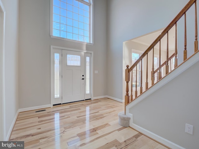 foyer featuring a towering ceiling and light hardwood / wood-style floors