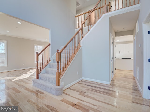 staircase featuring wood-type flooring and a high ceiling