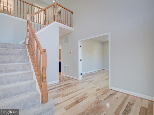 staircase featuring hardwood / wood-style floors and a towering ceiling