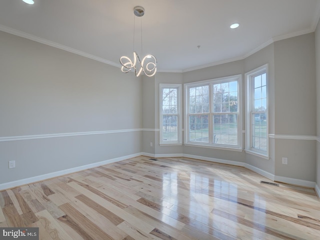 spare room with light wood-type flooring, crown molding, and a chandelier