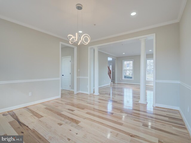 unfurnished dining area with light hardwood / wood-style floors, ornate columns, crown molding, and a notable chandelier