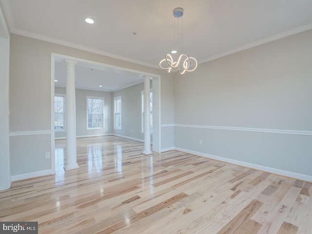 empty room with decorative columns, light hardwood / wood-style flooring, a chandelier, and ornamental molding