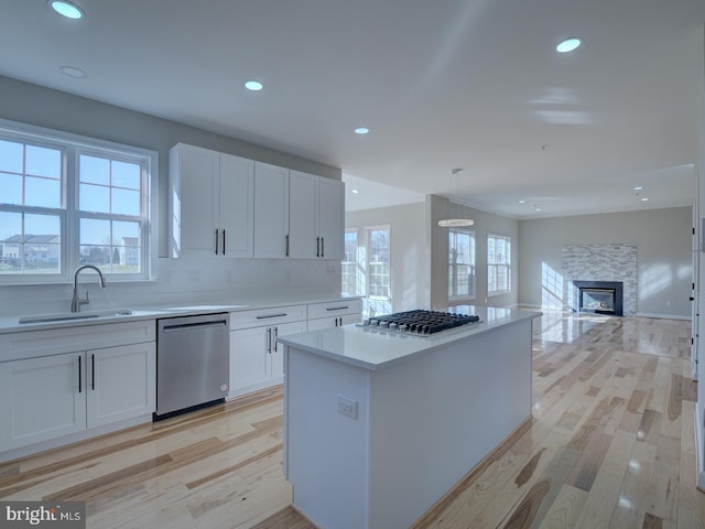 kitchen with light wood-type flooring, stainless steel appliances, white cabinetry, and sink