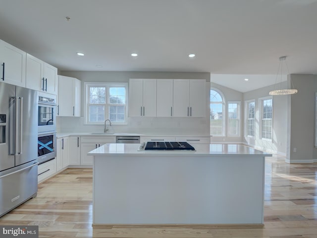 kitchen with plenty of natural light, white cabinets, light wood-type flooring, and appliances with stainless steel finishes