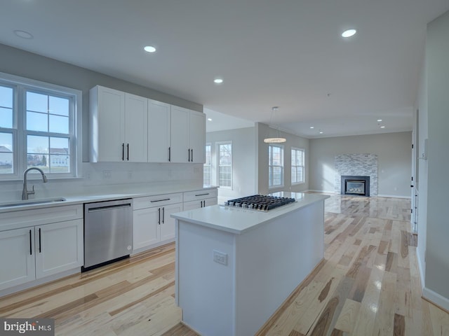 kitchen featuring white cabinetry, sink, decorative light fixtures, appliances with stainless steel finishes, and light wood-type flooring