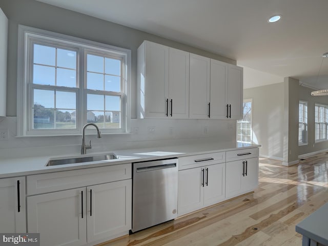 kitchen featuring decorative backsplash, stainless steel dishwasher, sink, light hardwood / wood-style flooring, and white cabinetry