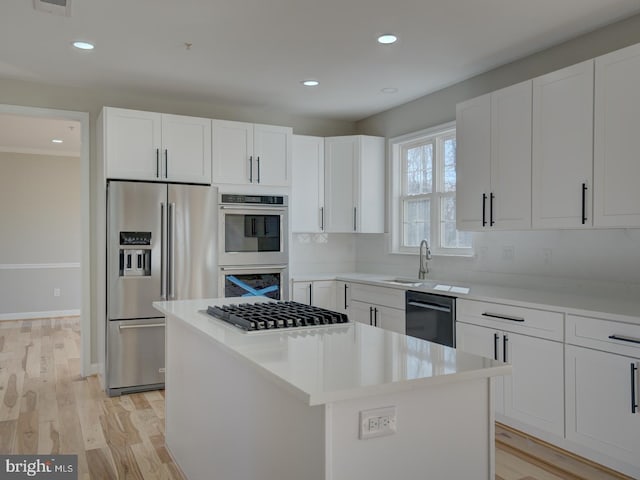 kitchen with a center island, backsplash, white cabinets, light hardwood / wood-style flooring, and appliances with stainless steel finishes