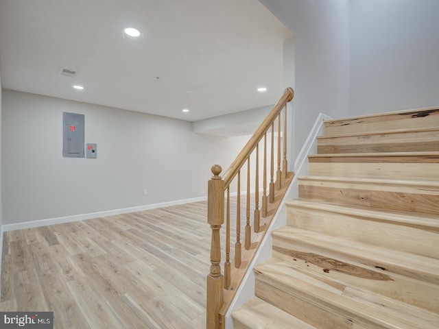 staircase featuring hardwood / wood-style floors and electric panel