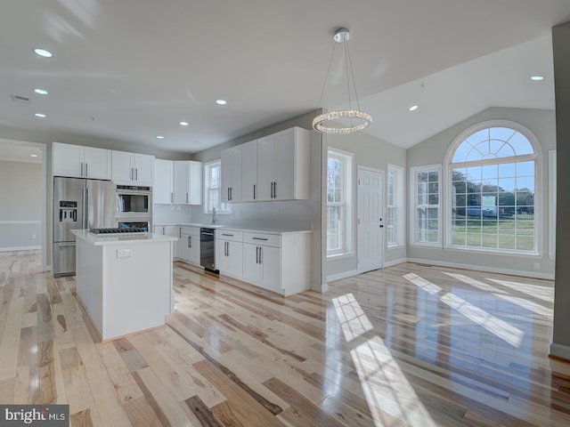 kitchen featuring a kitchen island, light hardwood / wood-style flooring, vaulted ceiling, decorative light fixtures, and white cabinets