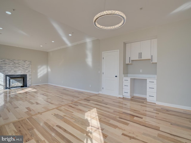 unfurnished living room with a stone fireplace, light hardwood / wood-style flooring, and ornamental molding