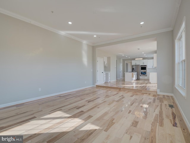 unfurnished living room with crown molding and light hardwood / wood-style floors