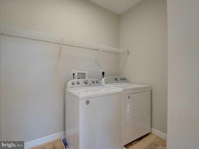 laundry area with washer and clothes dryer and light wood-type flooring