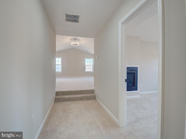 hall featuring light colored carpet and vaulted ceiling