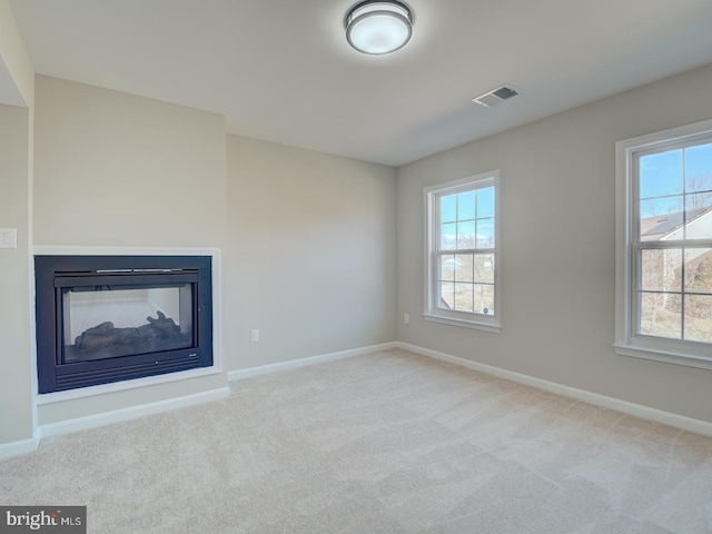 unfurnished living room featuring a multi sided fireplace and light colored carpet