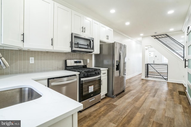 kitchen with white cabinetry, tasteful backsplash, light hardwood / wood-style flooring, appliances with stainless steel finishes, and ornamental molding