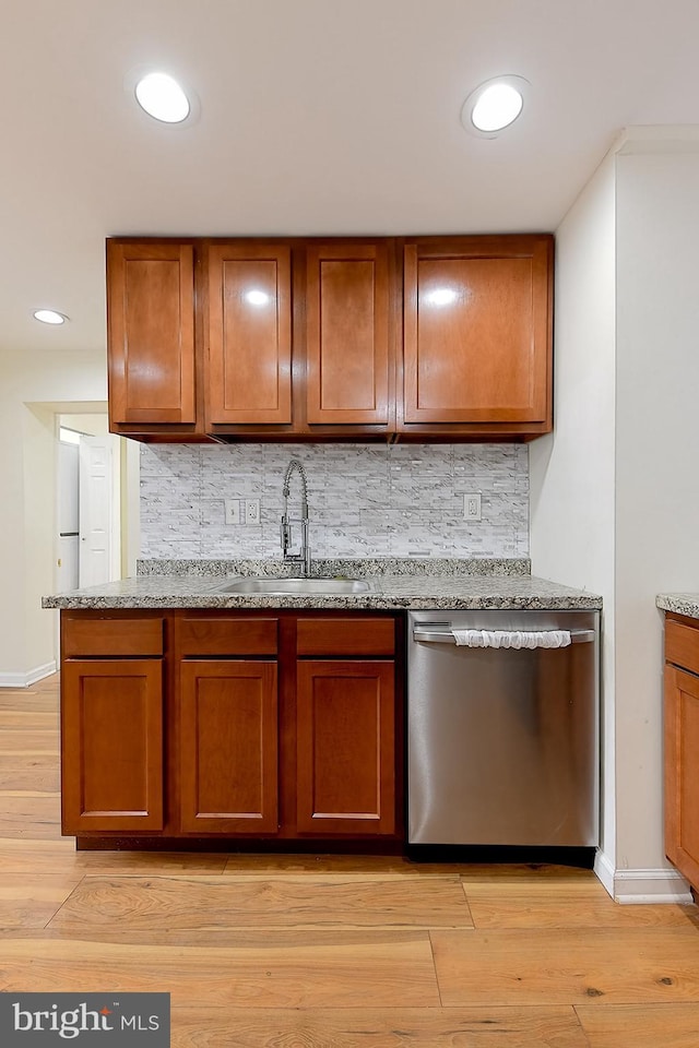 kitchen with backsplash, dishwasher, sink, and light hardwood / wood-style flooring