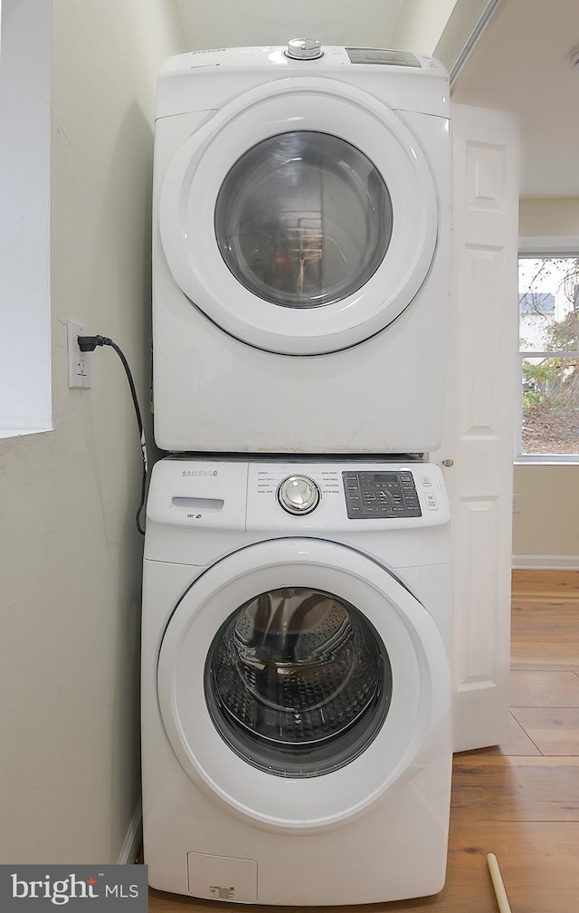 washroom with hardwood / wood-style floors and stacked washer and clothes dryer